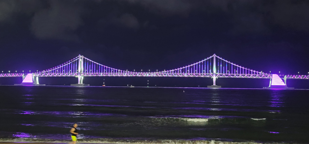 These pictures taken on Tuesday show landmark spots of Busan lit up in purple as part of the city's 