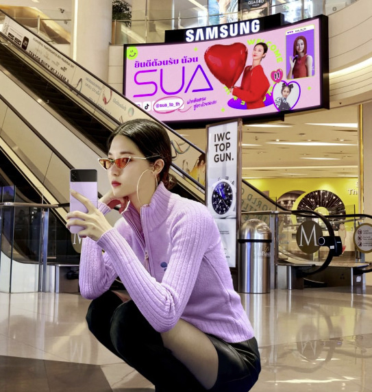 Onmind's AI virtual human Sua poses in front of a billboard in the Siam Paragon mall in Bangkok. (Sua's Thai Instagram account)