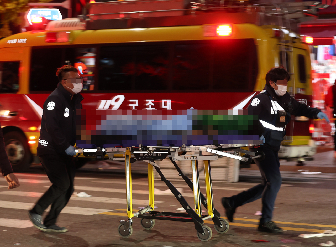 An injured person being transported by stretcher to an ambulance in Itaewon, central Seoul, where large-scale accident took place Saturday night, sending dozens into cardiac arrest. (Yonhap)