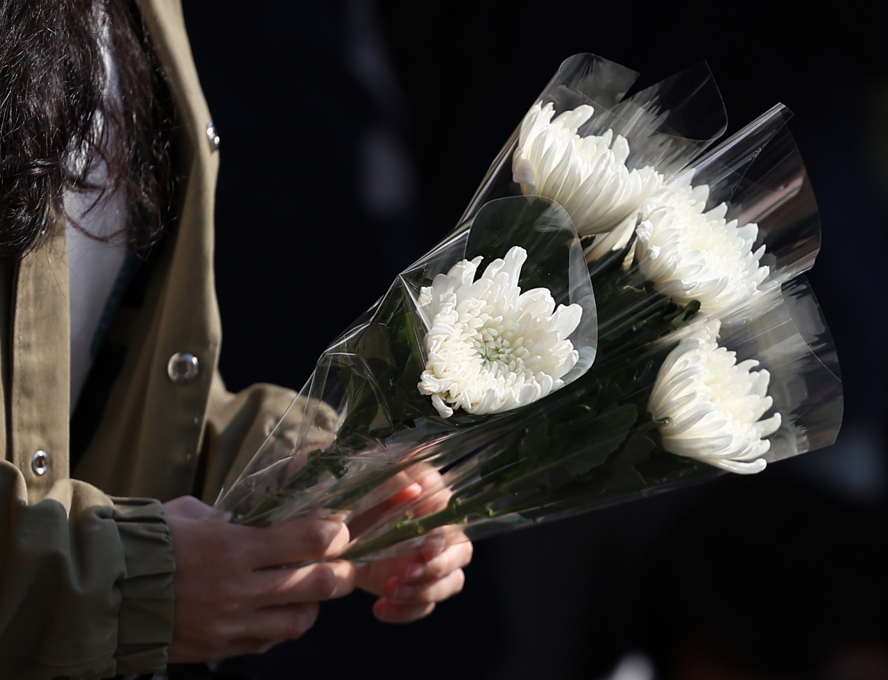 A mourner holds flowers that will be placed outside Itaewon subway station. (Yonhap)