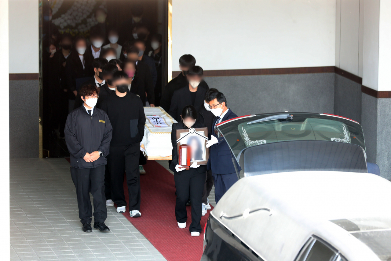 Relatives and friends follow the coffin of a victim of Saturday's Itaewon tragedy as it is placed in a funeral car on Tuesday. (Yonhap)