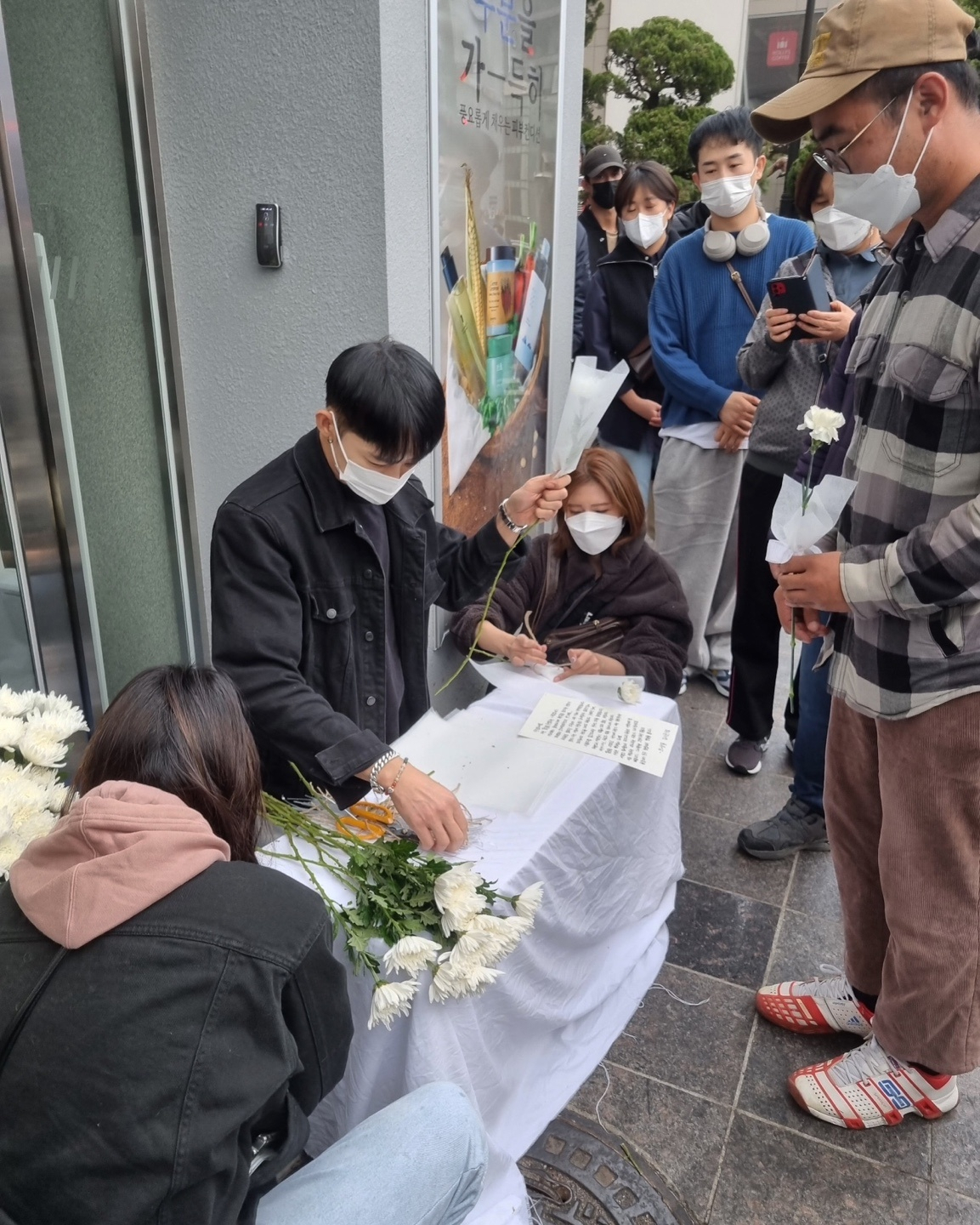 Kim Seo-joon gives out free flowers to mourners in front of Exit 1 of Itaewon Station inYongsan-gu, Seoul, Wednesday. (Choi Jae-hee / The Korea Herald)