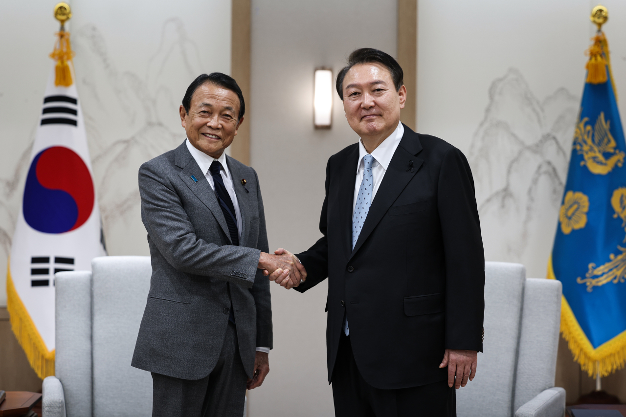 Yoon Suk-yeol (Right) shakes hands with former Japanese Prime Minister Taro Aso at the presidential office in Seoul on Wednesday, in this photo provided by his office.(Yonhap)