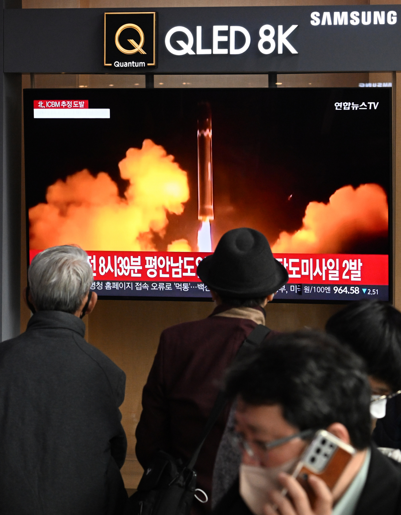 Passersby watch a news report on North Korean missile launches early Thursday at Yongsan Station in Seoul. (Im Se-jun/The Korea Herald)