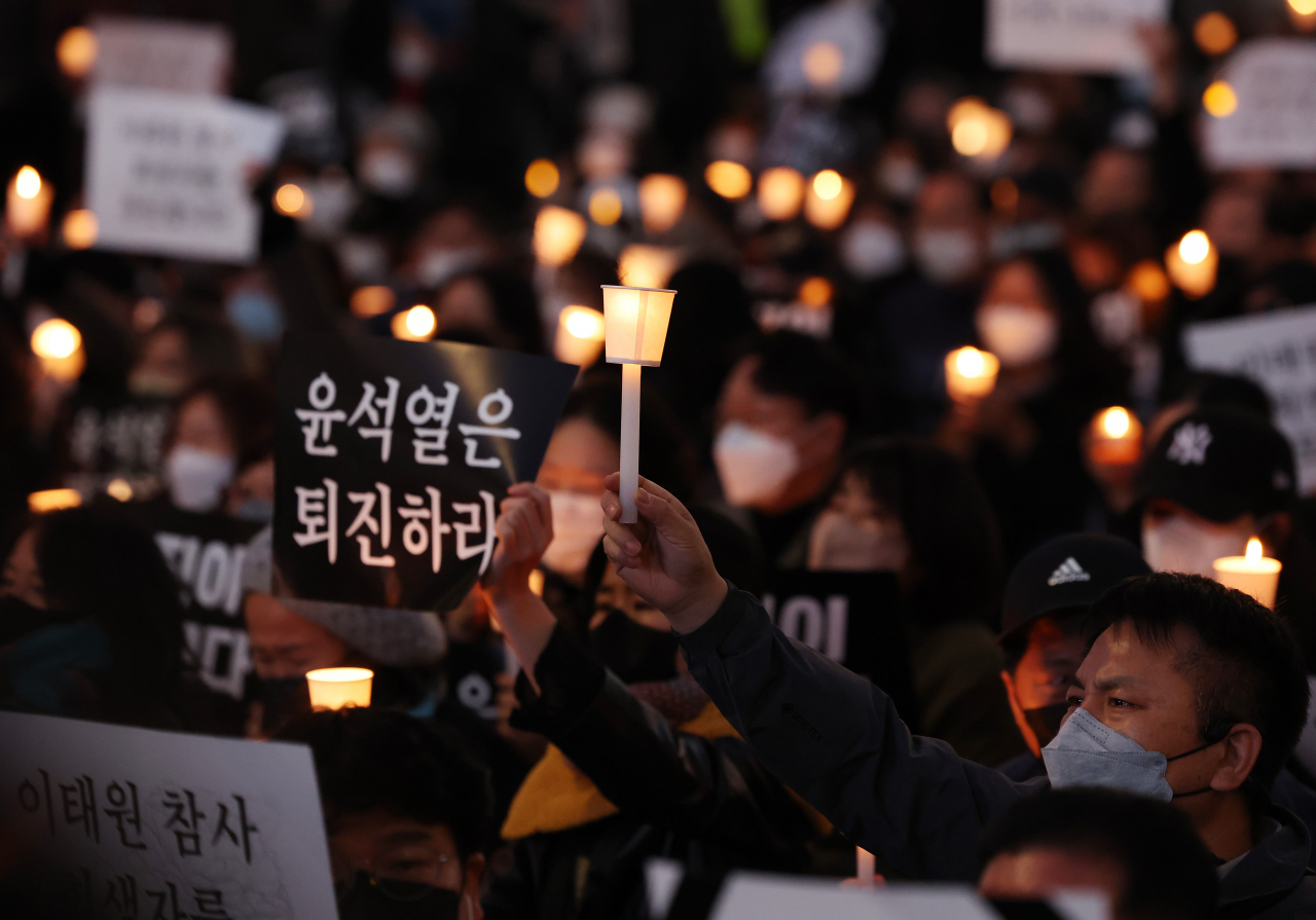 Participants hold candles and placards at a protest organized to commemorate victims who died in the Itaewon crowd crush, near Seoul City Hall in central Seoul on Saturday, the final day of the weeklong national mourning period. (Yonhap)