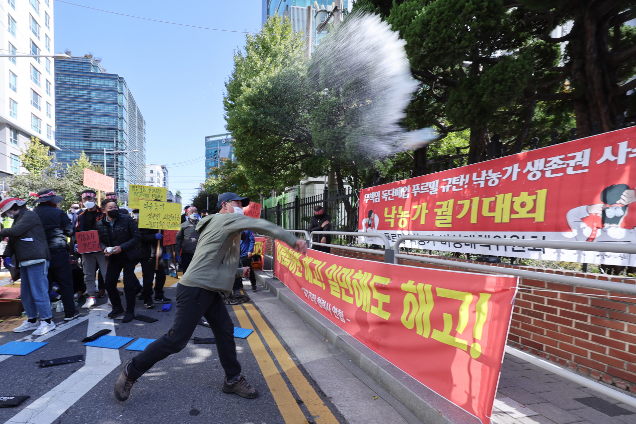 Raw milk supplier for Purmill throws milk at the Purmil headquarter building in Yeongdeungpo-gu, Seoul, on Oct. 25, protesting the company's decision to terminate its business. (Yonhap)