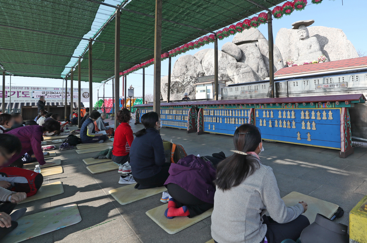 Pilgrims pray on Thursday in front of the Gatbawi stone Buddha statue in Gyeongsan, North Gyeongsang Province, with hopes of their children's success on the Suneung, which will come a week later. (Yonhap)