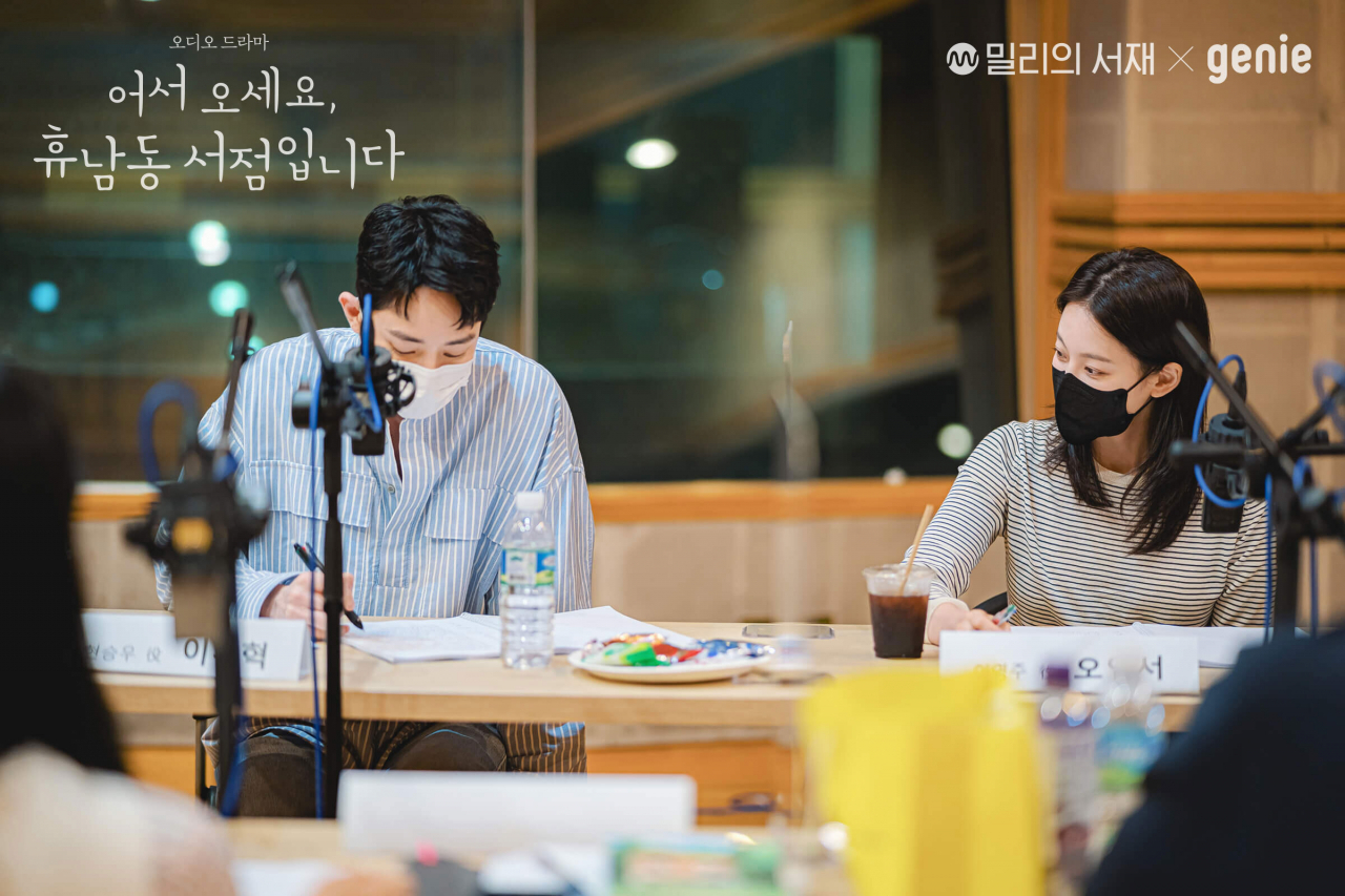 Lee Soo-hyuk (left) and Oh Yeon-seo record in an audio booth for the audio drama “Welcome to the Hyunam-dong Bookshop.