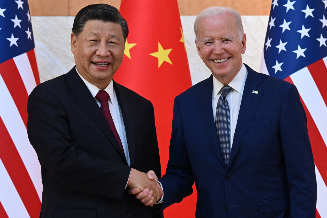 US President Joe Biden and Chinese President Xi Jinping hold hands during their first in-person bilateral summit in Bali, Indonesia on Monday. (Yonhap)