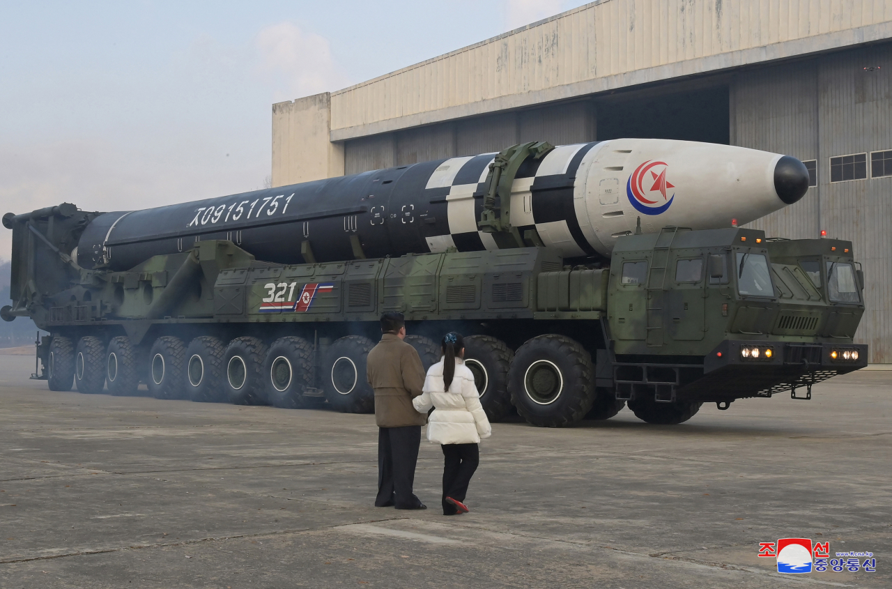 North Korean leader Kim Jong-un (left), alongside his daughter wearing a winter jacket, views a new type of the Hwasong-17 intercontinental ballistic missile during an on-site inspection of the missile launch at Pyongyang International Airport last Friday. (KCNA)