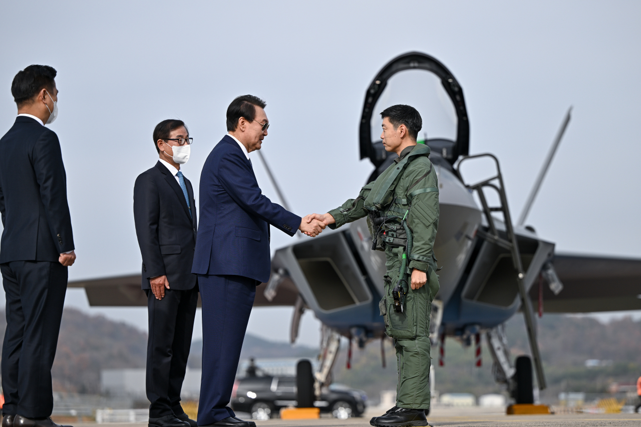 President Yoon Suk-yeol (second from right) shakes hands with Lt. Col. Lee Jin-wook, a KF-21 pilot, during his visit to the Korea Aerospace Industries in Sacheon, South Gyeongsang Province, Thursday morning. (Yonhap)