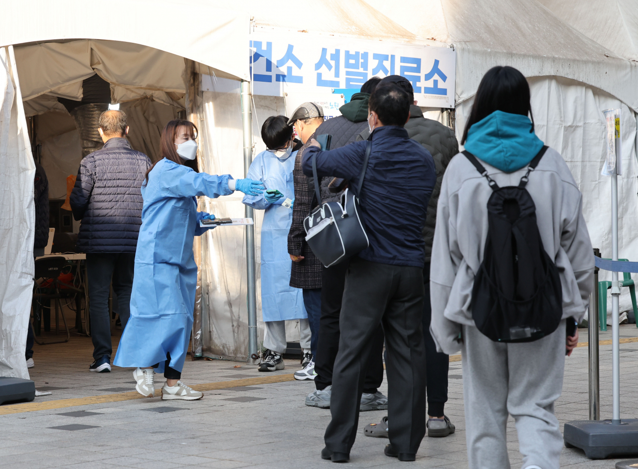 A medical workder guides people at a COVID-19 test center in Seoul on Monday. (Yonhap)