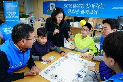 SC Bank Korea employees and blind students play a Braille board game donated by the bank. (SC Bank Korea)