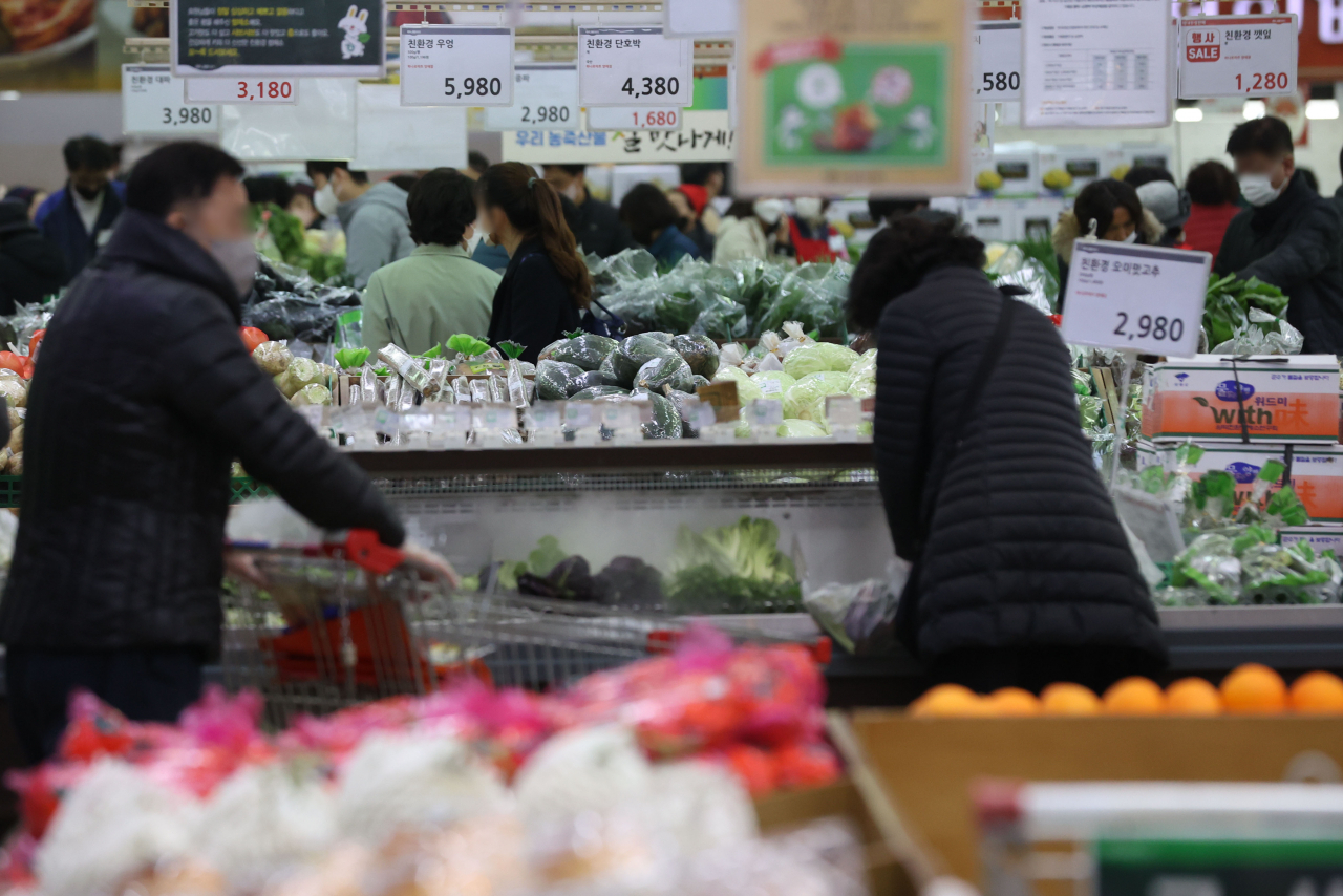 Shoppers choose vegetables at a supermarket in Seoul last Sunday. (Yonhap)