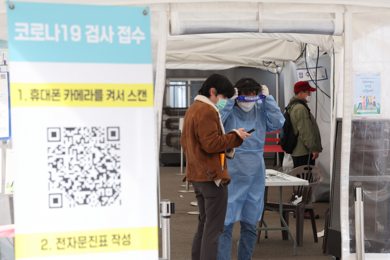 A citizen talks to a medical worker at a COVID-19 testing center in Seoul last Sunday. (Yonhap)