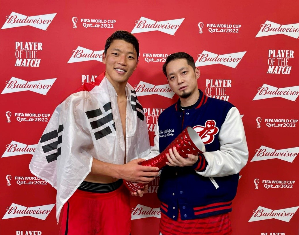 South Korean footballer Hwang Hee-chan (left) poses with rapper The Quiett after recieving Budweiser's 2022 FIFA World Cup Player of the Match trophy on Saturday, following South Korea's soccer match against Portugal held in the Education City Stadium in Al-Rayyan, Qatar.