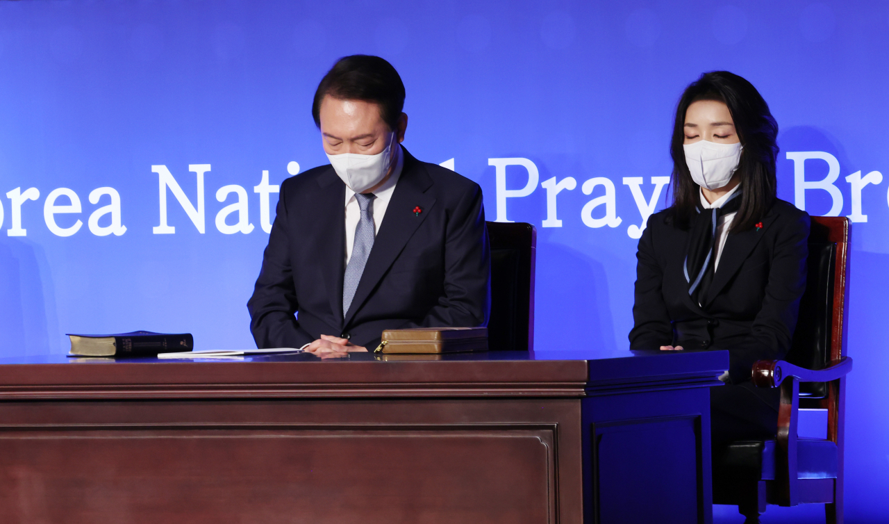 President Yoon Suk-yeol (left) and first lady Kim Keon-hee pray during a national prayer breakfast in Seoul on Monday. (Yonhap)