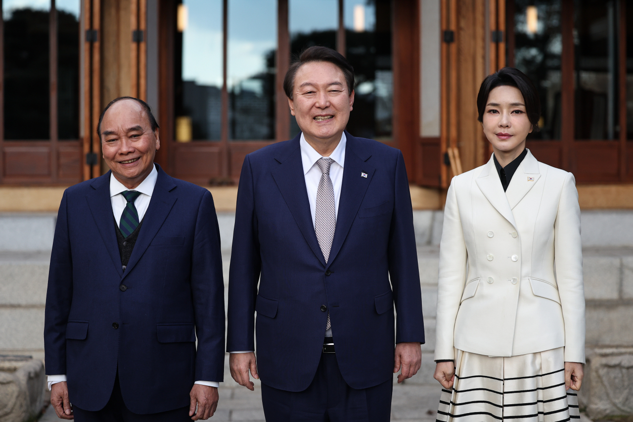 Vietnamese President Nguyen Xuan Phuc (left), South Korean President Yoon Suk-yeol (center) and his wife Kim Keon-hee pose in front of Sang Chun Jae, a wooden pavilion that hosts VIP guests at Cheong Wa Dae, Tuesday. (Presidential Office)