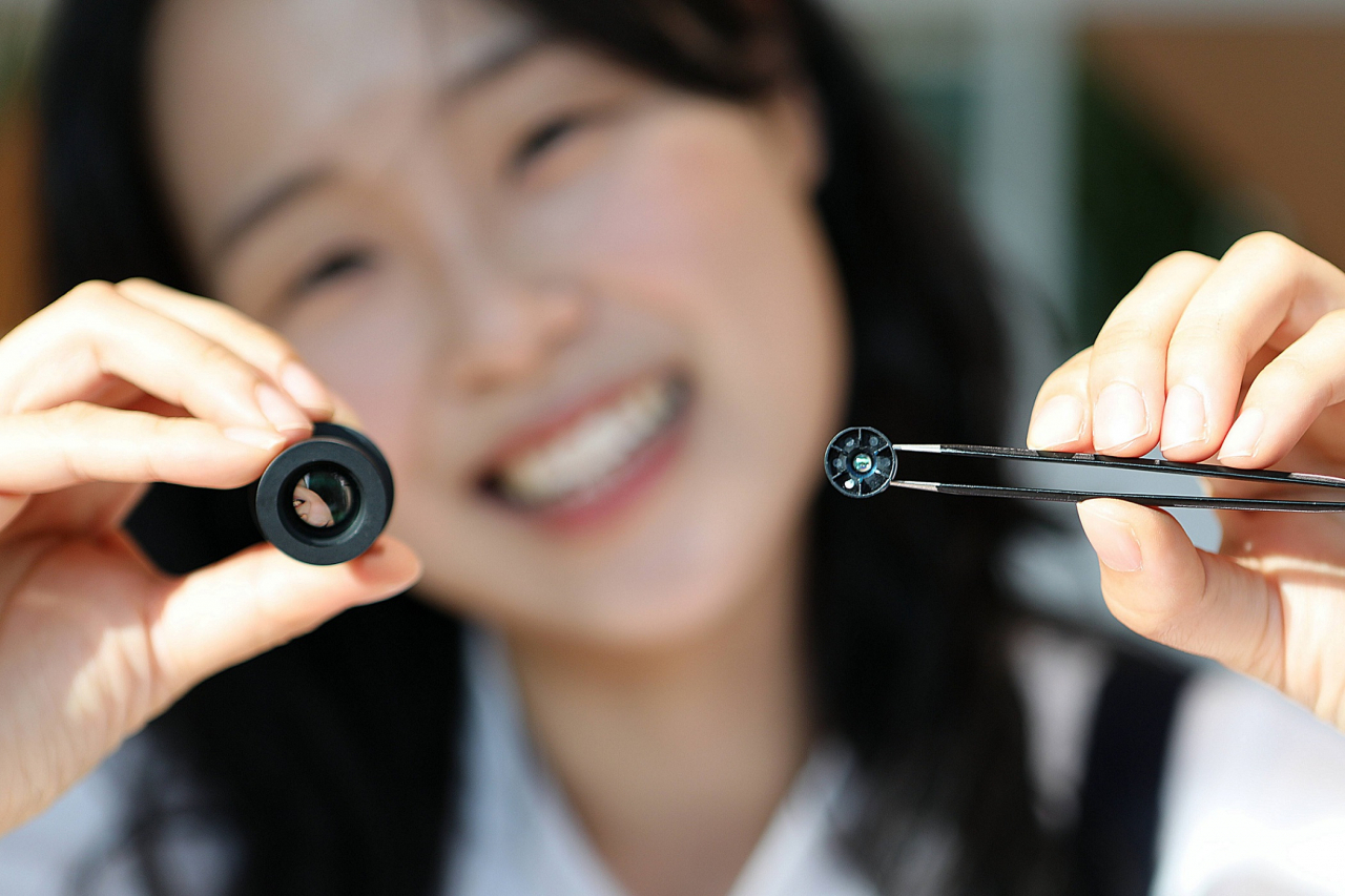 A LG Innotek employee holds up the newly developed high-performance hybrid lenses, to be used in the Driver Monitoring System (right) and in the Advanced Driver Assistance System (left). (LG Innotek)