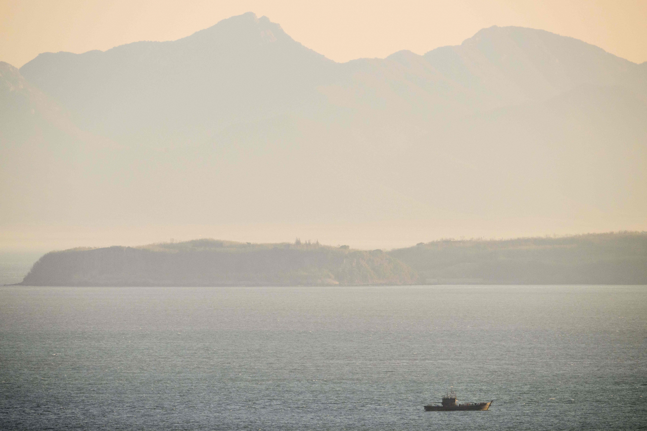 In this picture taken on Oct. 28, a fishing vessel is seen in North Korean waters near North Korea's mainland, as photographed from a viewing point on Baekryeong Island, located two kilometres from the de facto maritime border and just 14 kilometres from the North Korean mainland. Far closer to the North Korean mainland than it is to the South, Baekryeong is a fortress: tanks are parked at the sides of roads, there are guard posts on every hill, and the picturesque beaches are covered in 