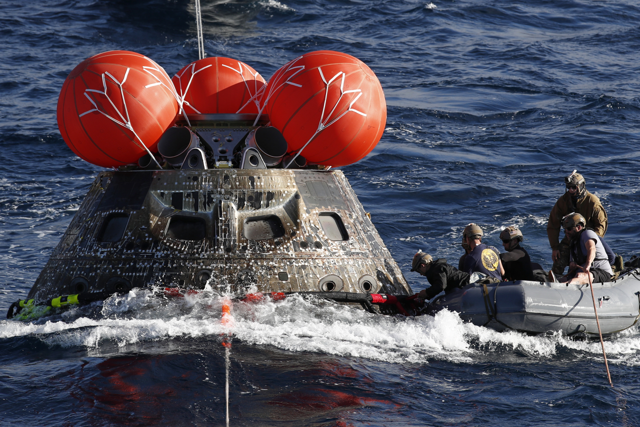US Navy divers attach winch cables to NASA's Orion capsule after being successfully secured off the coast of Baja California, Mexico, Sunday. (UPI-Yonhap)