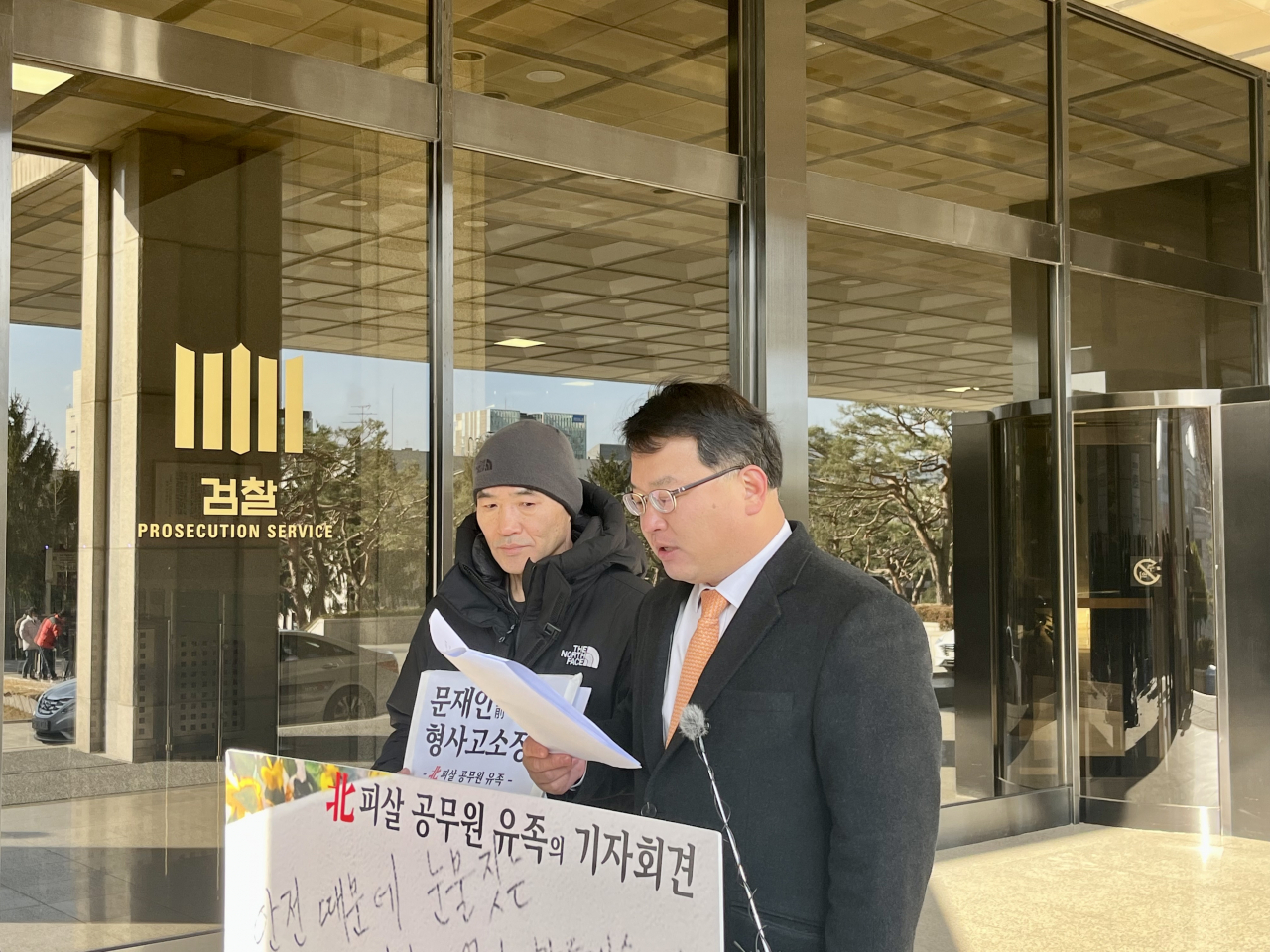 Lee Rae-jin, the brother of the South Korean official who was shot dead by North Korean soldiers at sea in 2020, (left) speaks to reporters outside the Seoul central district prosecutors’ office on Wednesday. On the right is his lawyer, Kim Ki-yun. (Kim Arin/The Korea Herald)