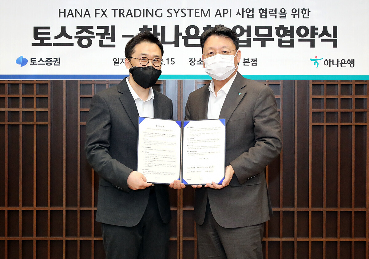 Toss Securities CEO Oh Chang-hoon(left) and Hana Bank official Namgoong One pose for a photo after signing a memorandum of understanding to jointly provide around-the-clock service for FX trading. (Hana Bank)
