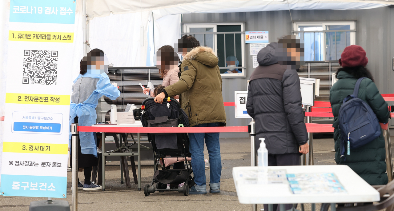 This photo shows people standing in line at a COVID-19 screening center by Seoul Station last Sunday. (Yonhap)