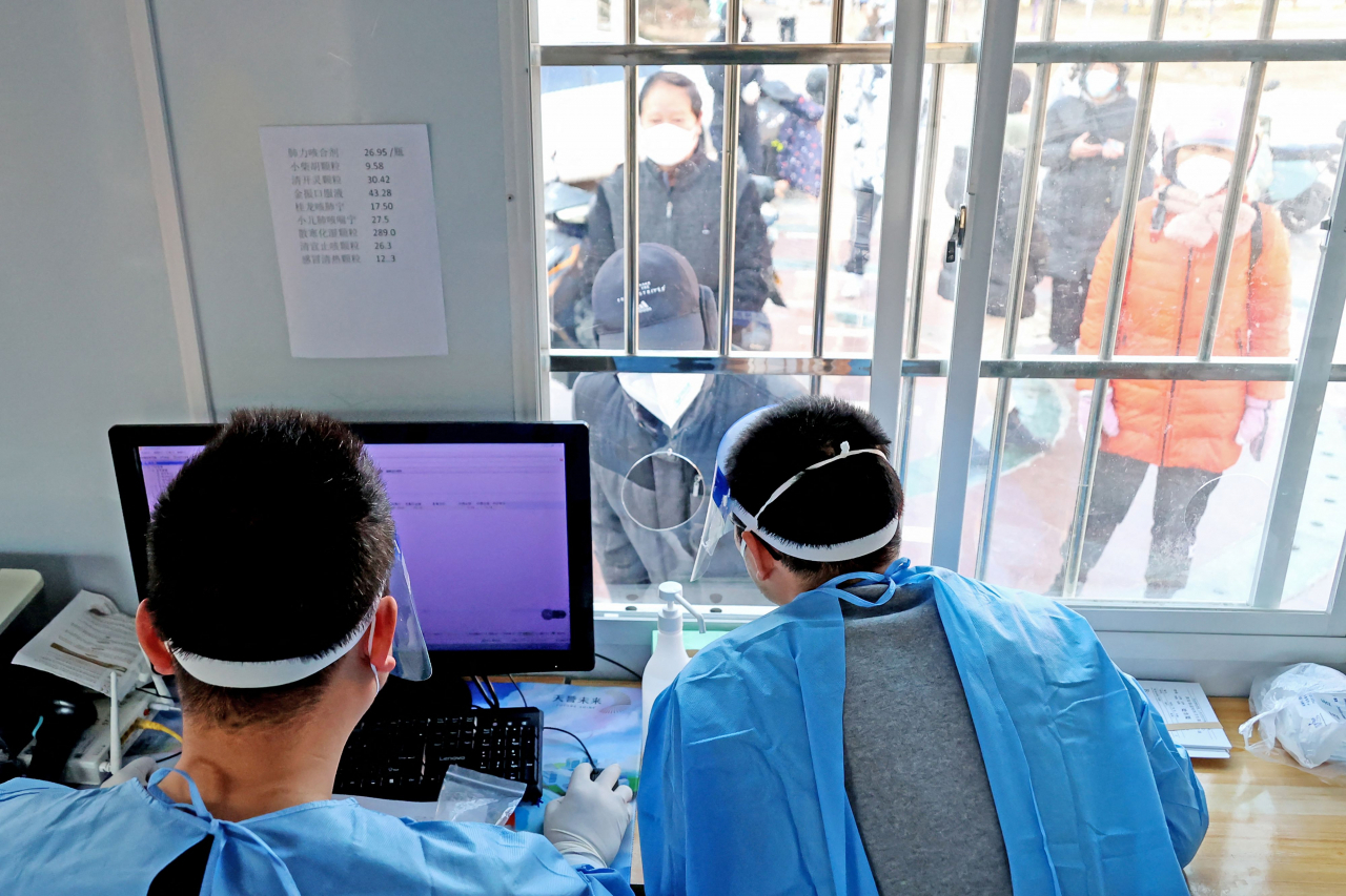 Staff members work at a medical service facility as people queue outside in Lianyungang, in China's eastern Jiangsu province on Thursday. (AFP)