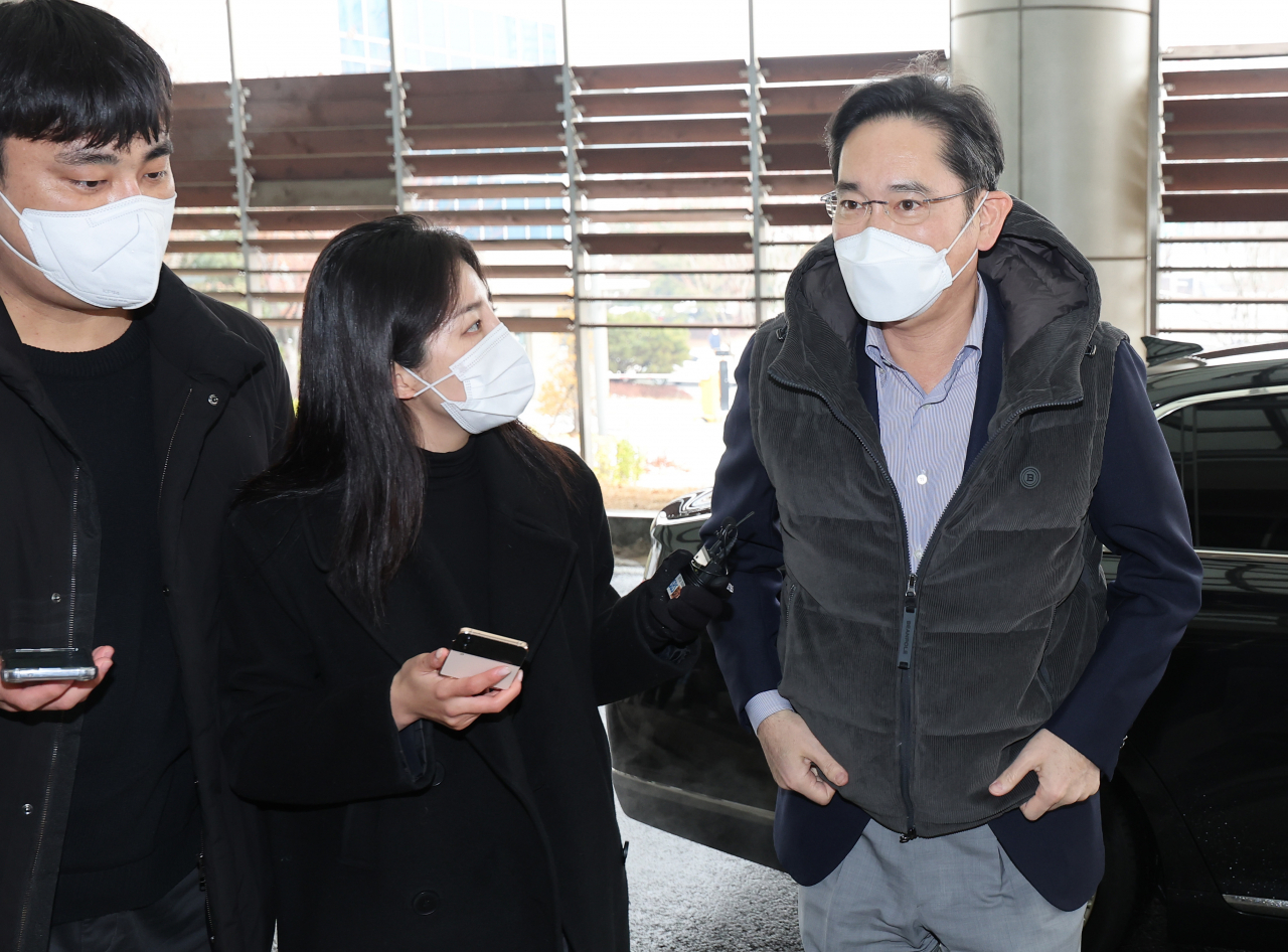 Samsung Electronics Chairman Lee Jae-yong (right) faces reporters on Wednesday at Gimpo International Airport, wearing a Beanpole puffer vest, before boarding a chartered Korean Air flight to Vietnam to attend the inauguration ceremony of a Samsung R&D center. (Yonhap)