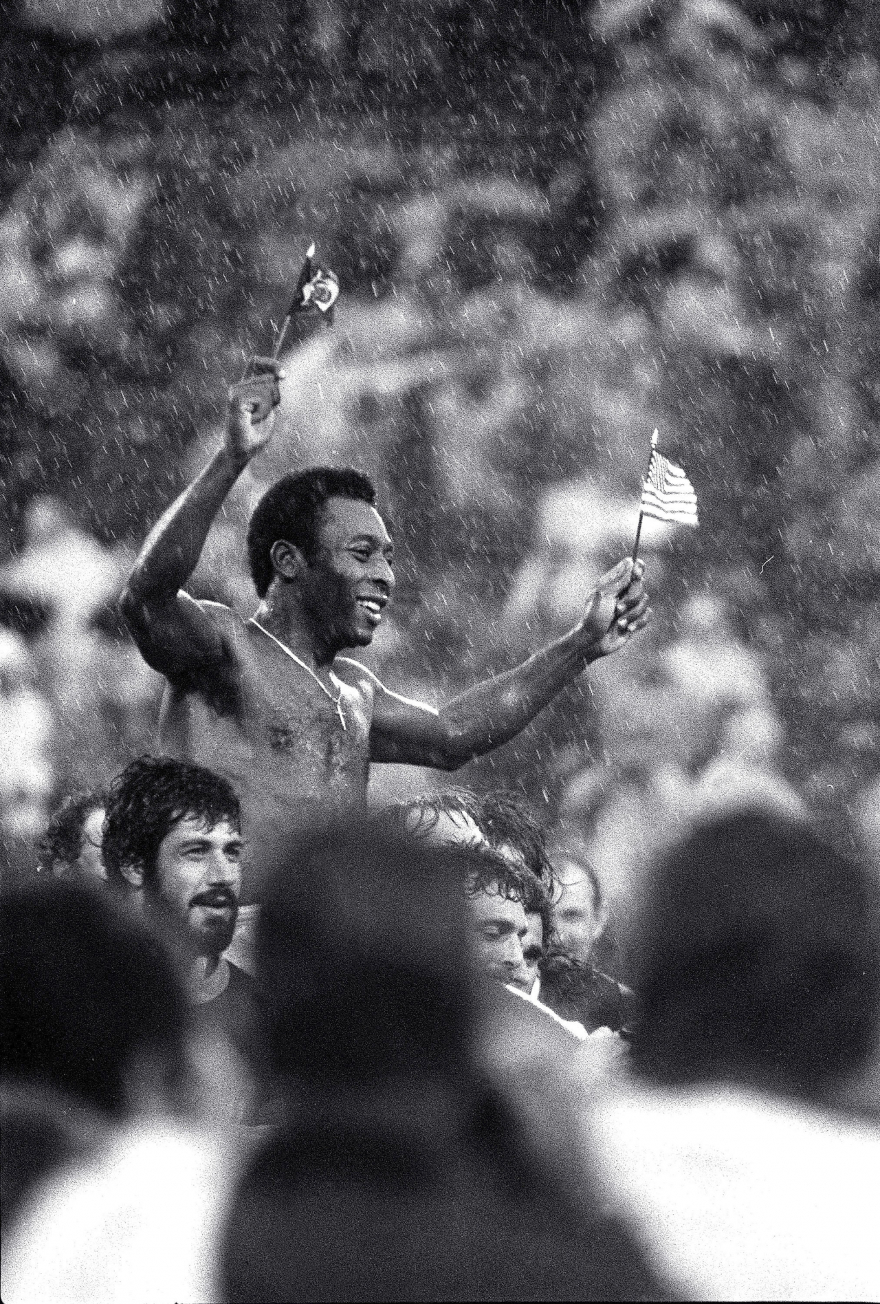 Soccer superstar Pele, waving the flags of Brazil and the US, is carried off the field in driving rain by players of both teams at Giants Stadium in East Rutherford, N.J., after his final game, Oct. 1, 1977. (AP)