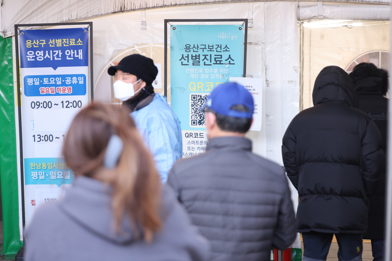 Pedestrians stand in line to receive COVID-19 tests at a testing center in Yongsan, Seoul, Monday. (Yonhap)