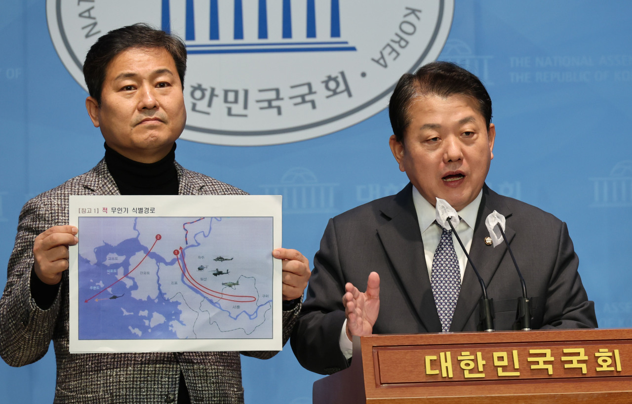 Rep. Kim Byung-joo (R) of the main opposition Democratic Party speaks at a news conference on Friday at the National Assembly in western Seoul while Kim Young Bae of the Democratic Party (L) holds an image of a map that shows the identified flight paths of North Korean drones that intruded into South Korea's airspace. (Yonhap)