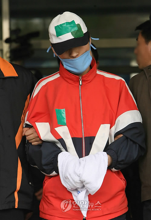 Jeong Nam-kyu is escorted out of a police station in Seoul to participate in a crime scene reenactment, April 2006. (Yonhap)