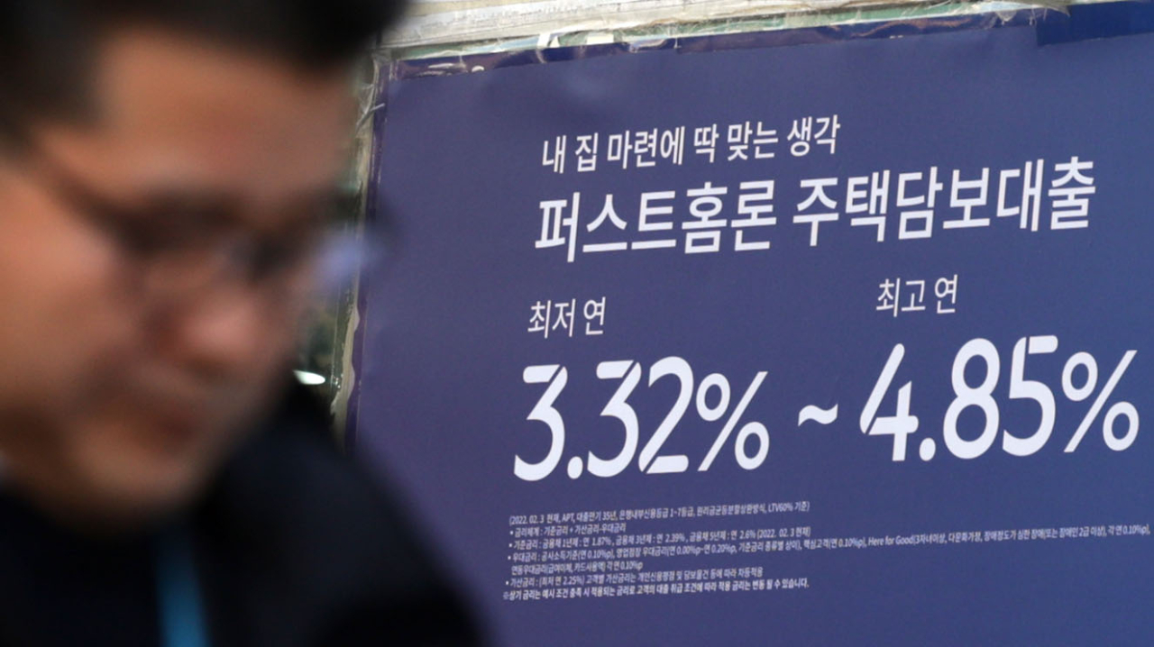 A man passes by an advertisement in front of a local bank promoting its mortgage product, in this photo taken on Jan. 3. (Yonhap)