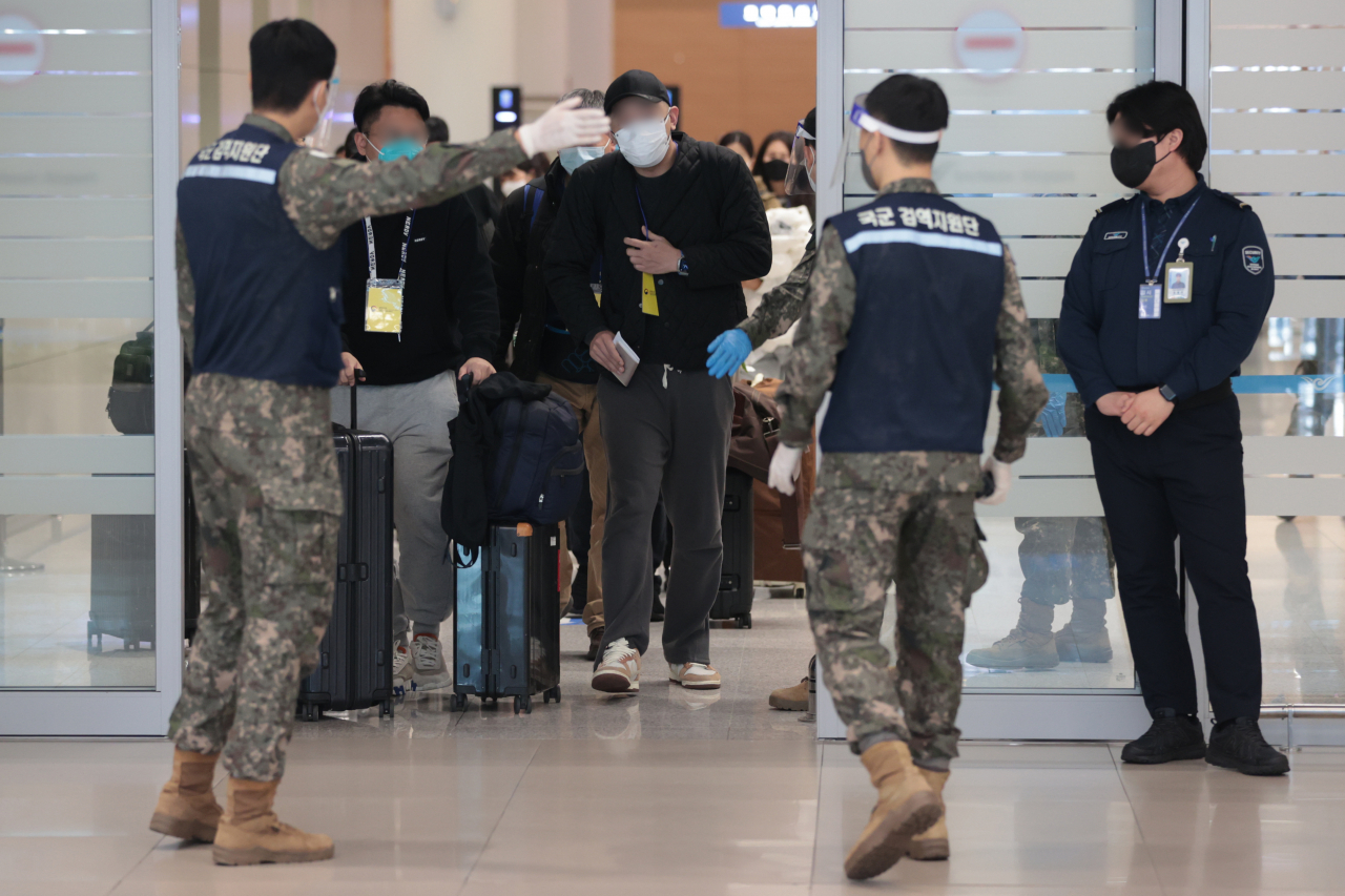 People traveling from China to South Korea are seen following the instruction of the Korean military personnels at Incheon Airport on Monday. (Yonhap)