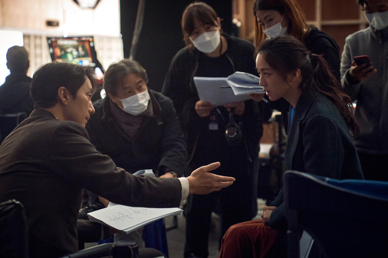 Park Chan-wook (center) speaks with the two lead actors, Tang Wei (right) and Park Hye-il, on the set of “Decision to Leave.” (CJ ENM)