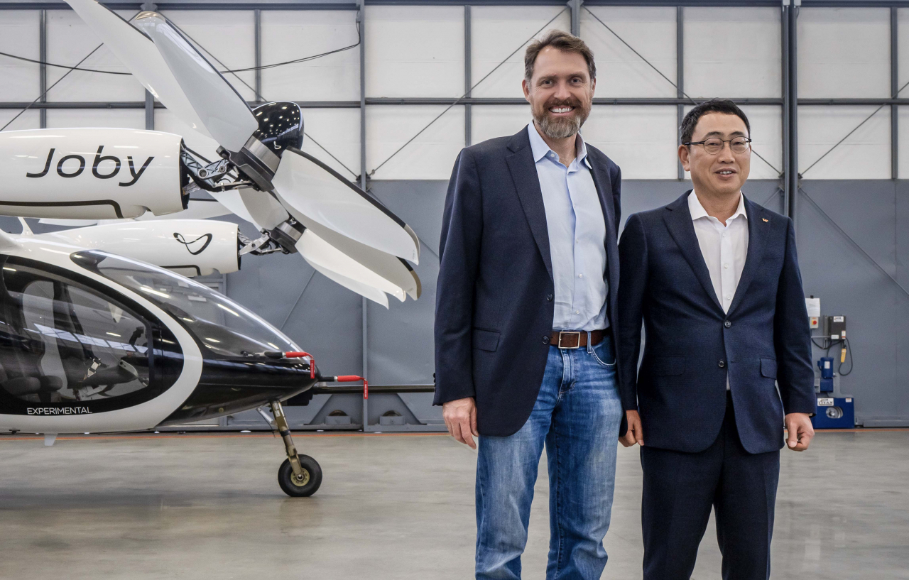 Joby Aviation CEO JoeBen Bevirt (left) and SK Telecom CEO Yoo Young-sang pose in front of an urban air mobility aircraft in Joby Aviation's production facilities in San Jose, California. (SK Telecom)