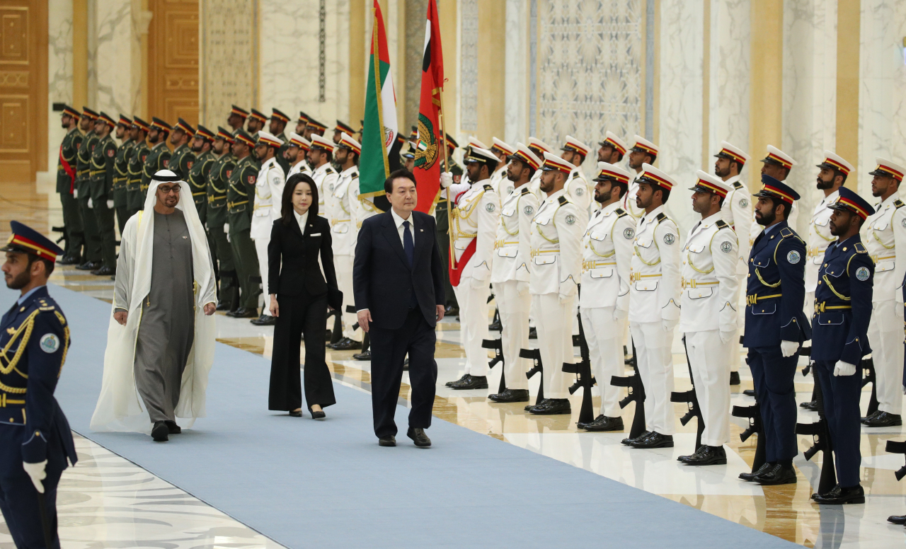 South Korea's President Yoon Suk Yeol and his wife Kim Keon Hee (center) walk alongside Emirati President Sheikh Mohammed bin Zayed al-Nahyan (left) during a welcome ceremony at the royal palace in Abu Dhabi, United Arab Emirates, on Sunday. (Yonhap)