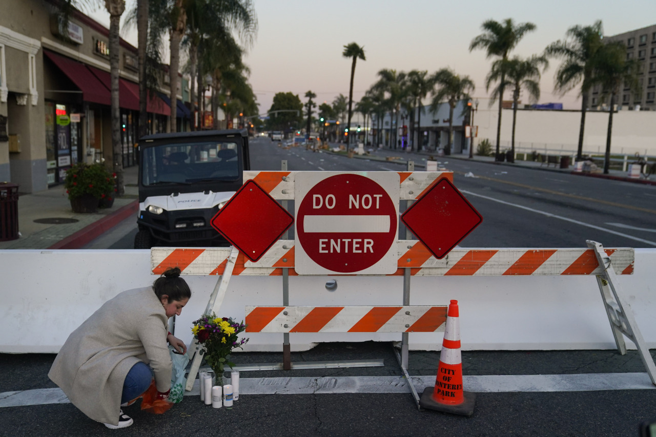 A person leaves flowers and candles on Sunday to honor the victims killed in Saturday's ballroom dance studio shooting in Monterey Park, California. (AP Photo)