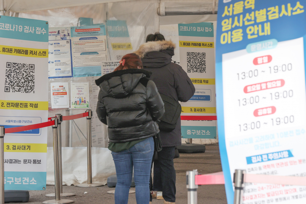 People wait to receive COVID-19 tests at a makeshift clinic in central Seoul on Monday. (Yonhap)