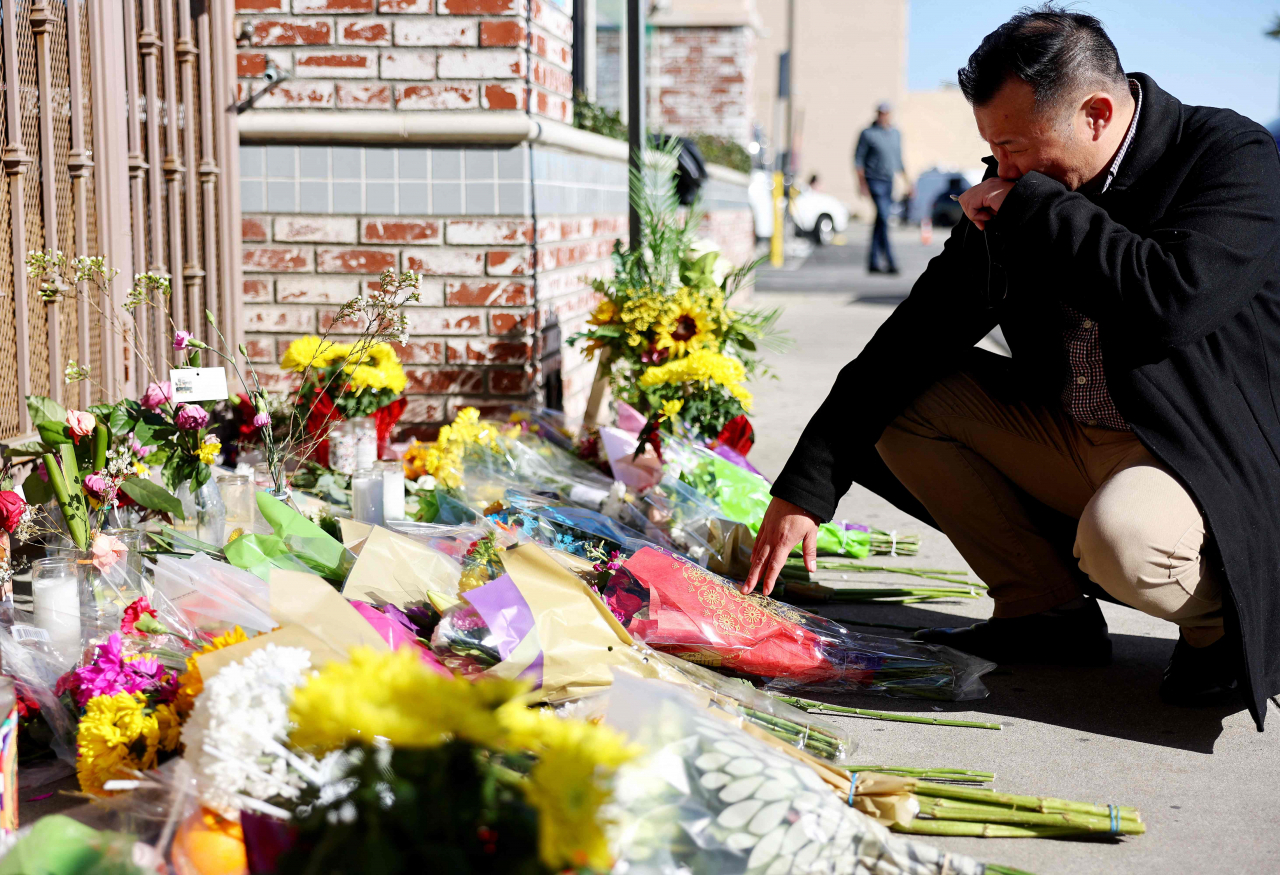 Monterey Park Mayor Henry Lo kneels at a makeshift memorial outside the scene of a deadly mass shooting at a ballroom dance studio in Monterey Park, California, Monday (AFP-Yonhap)