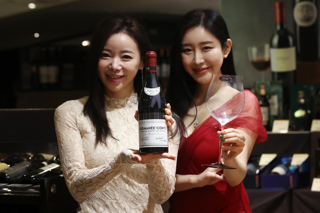 Models pose with a bottle of wine at Lotte Department Store in central Seoul in this file photo taken on Jan. 12, 2023 (Yonhap)