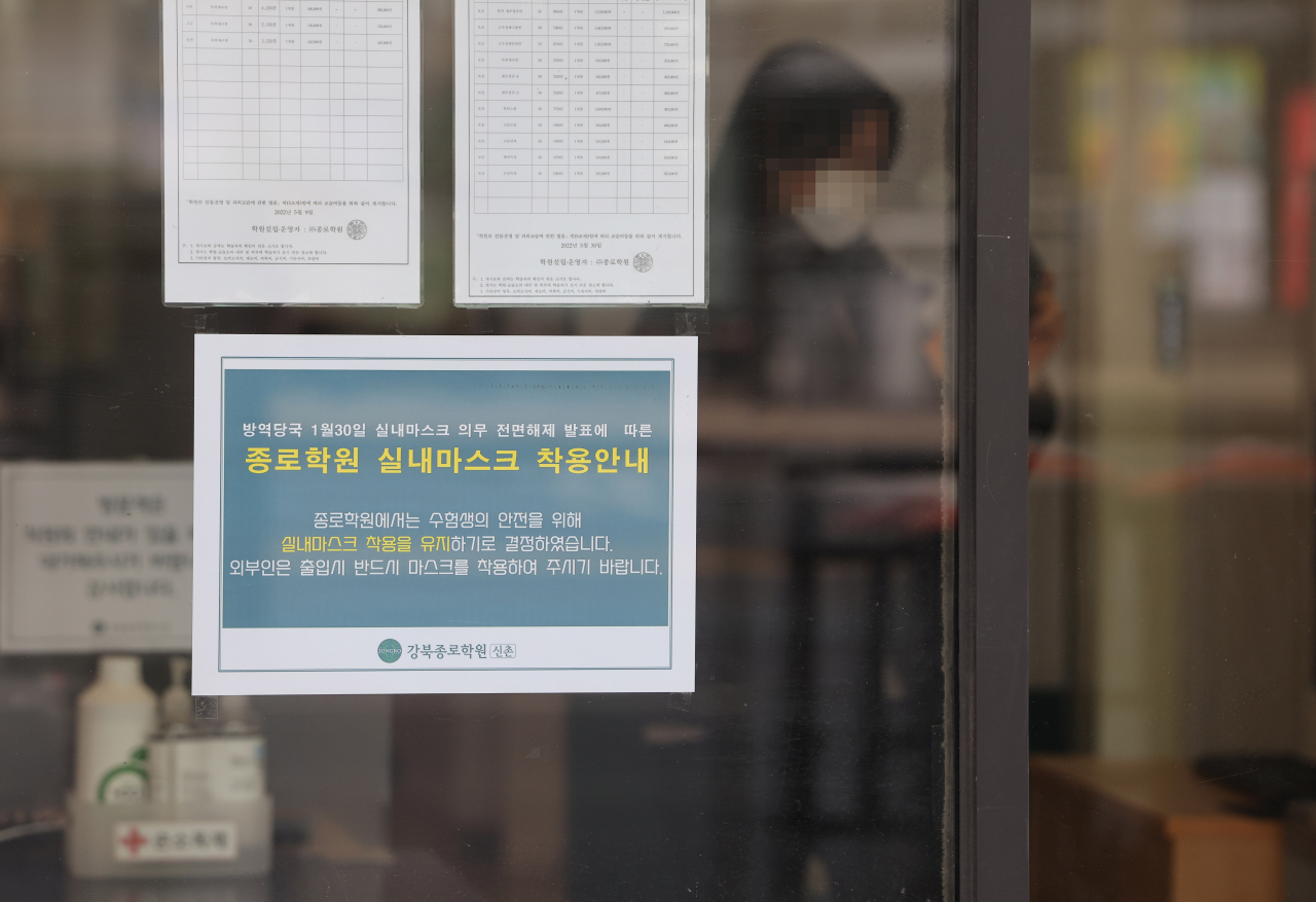 A notice asking people to wear masks indoors is posted at Jongno Academy in Mapo-gu, Seoul, Sunday. From Monday, indoors mask mandates will be lifted at many places including private cram schools, but many have reportedly decided to maintain their own guidelines for wearing masks. (Yonhap)