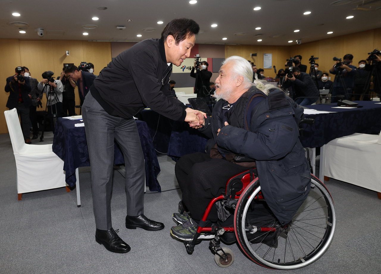 Seoul Mayor Oh Se-hoon (left) shakes hand with Park Kyoung-seok, chief of Solidarity Against Disability Discrimination, before the meeting held at the Seoul Metropolitan Government on Thursday. (Joint Press Corps)