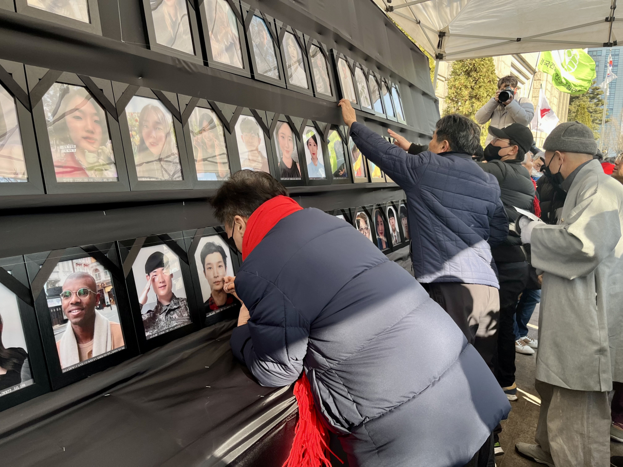 A father wipes the framed portrait of his son on the memorial altar installed outside Seoul City Hall on Saturday. (Kim Arin/The Korea Herald)
