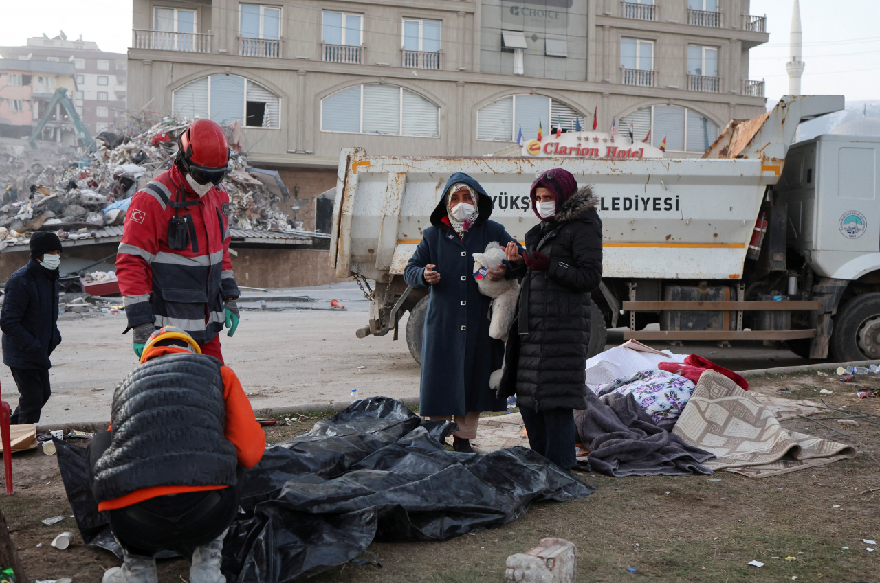 A woman with a teddy bear stands near the bodies of victims, in the aftermath of a deadly earthquake in Kahramanmaras, Turkey on February 14, 2023. (Reuters-Yonhap)