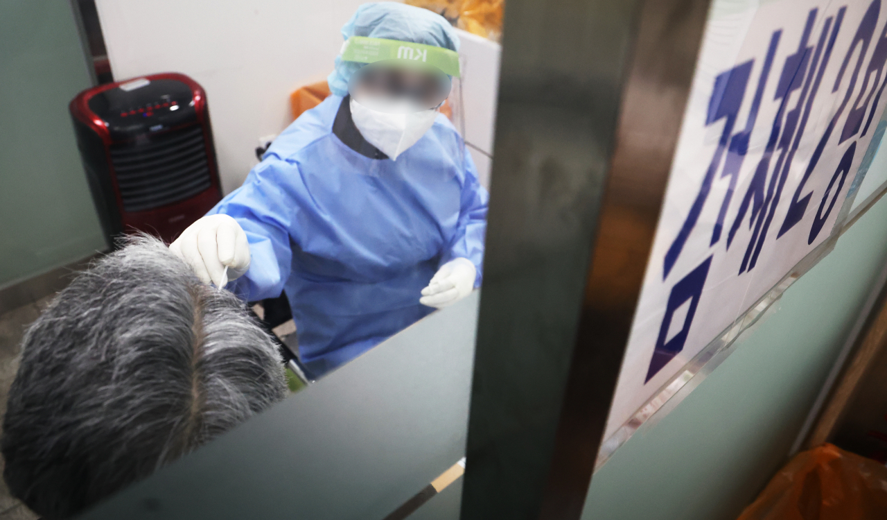 A health worker conducts a coronavirus test at a testing center in Mapo, Seoul, on Monday. (Yonhap)