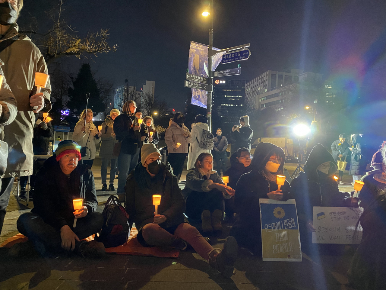 People hold candles in a vigil commemorating the one year anniversary of Russia’s war against Ukraine on Friday near the Russian embassy in Seoul. (Lim Jae-seong/The Korea Herald)