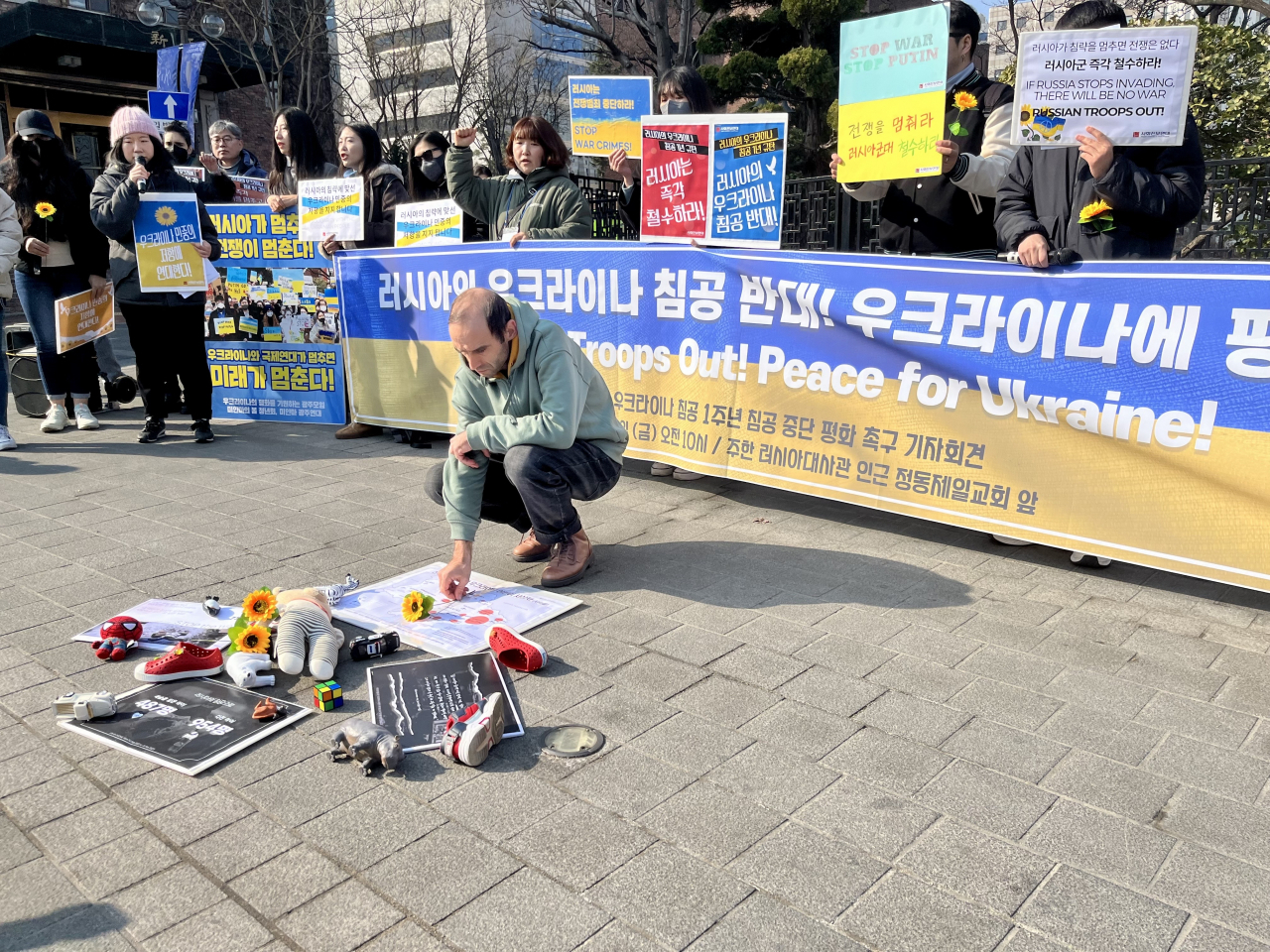 Andrei Litvinov, a Ukrainian teacher at a school for Koryoin children in Gwangju, lays a flower in remembrance of the children who died in the war in Ukraine during a rally outside the Russian embassy on Friday. (Kim Arin/The Korea Herald)